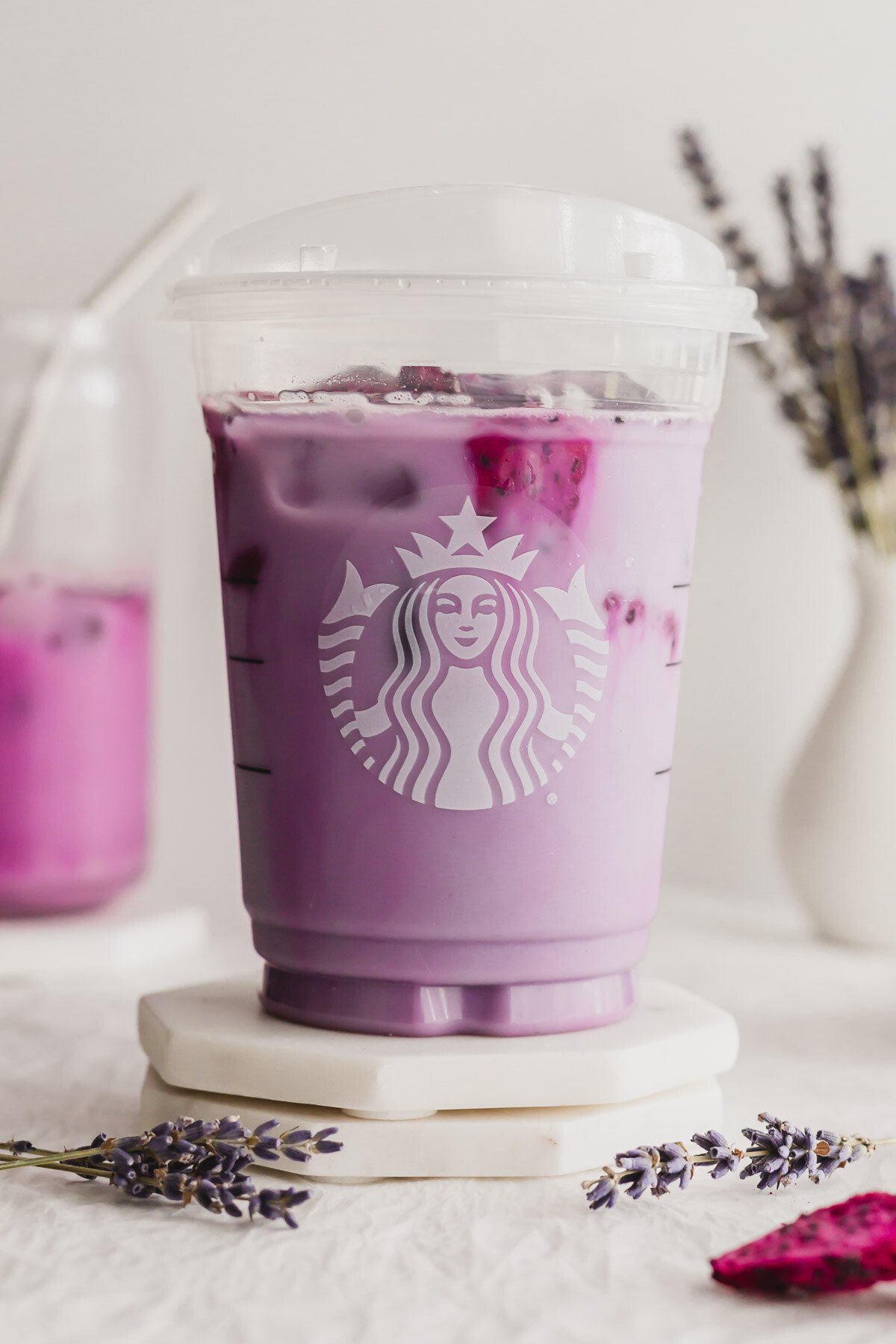 Close up of Lavender oat chill in a Starbucks plastic cup, on marble coasters.