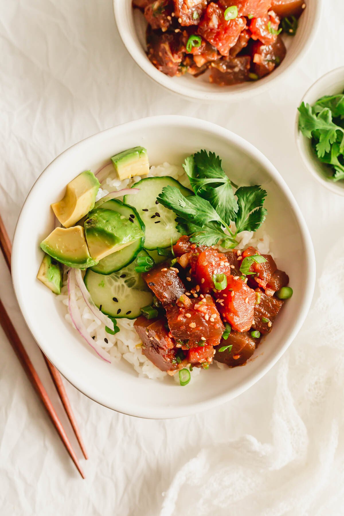 Spicy tuna poke in a white bowl with rice and toppings.