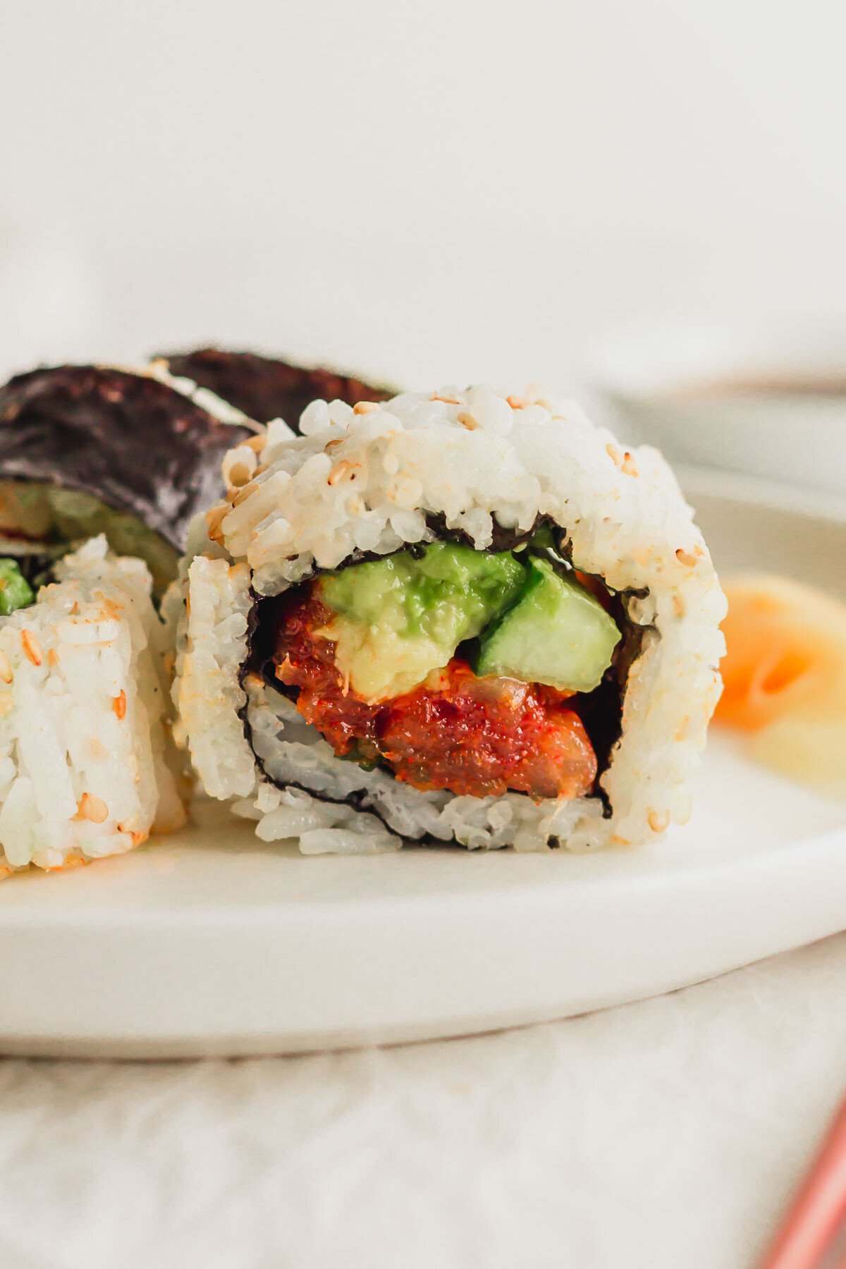 Close up of spicy tuna sushi rolls on a white plate.