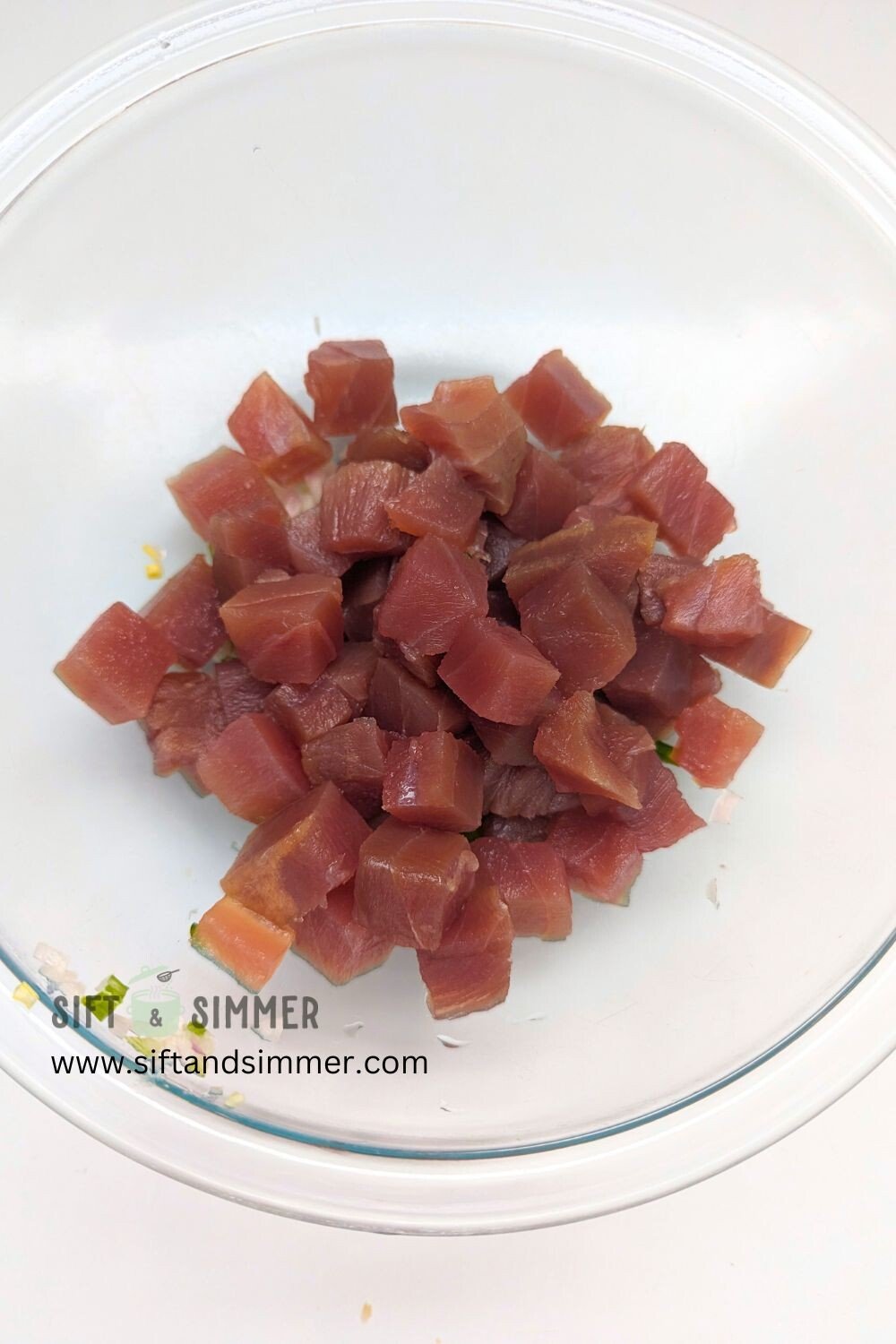 Cubed ahi tuna in a glass bowl.