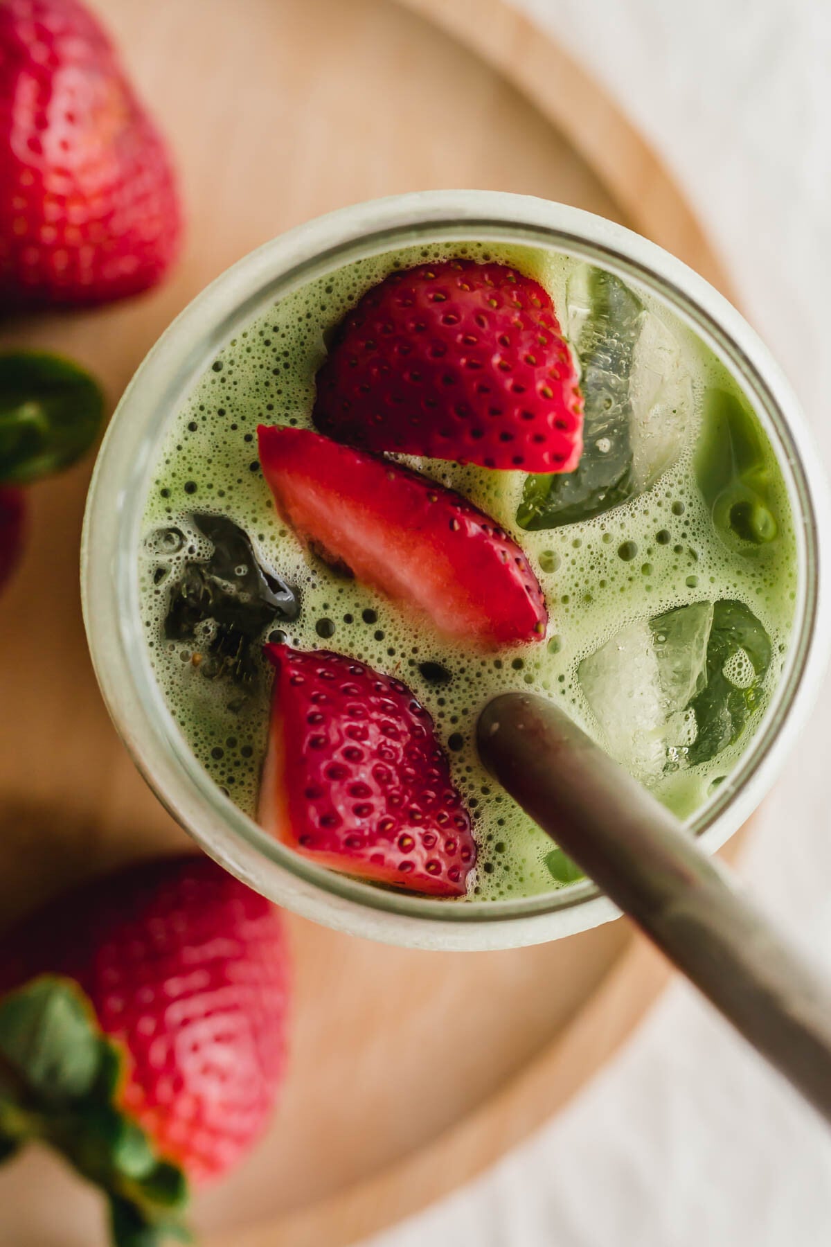 Matcha strawberry latte in a glass with steel straw.