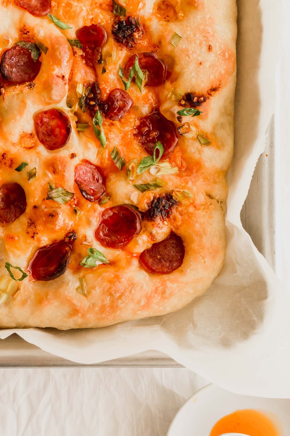 Chili oil focaccia with Chinese sausage on a baking sheet with parchment paper.