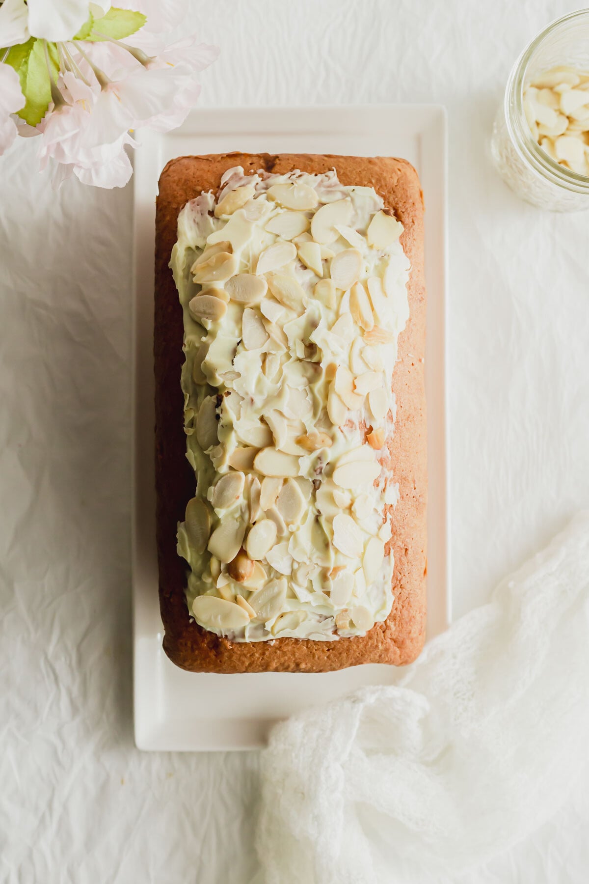 Unsliced almond pound cake on a white rectangular plate.