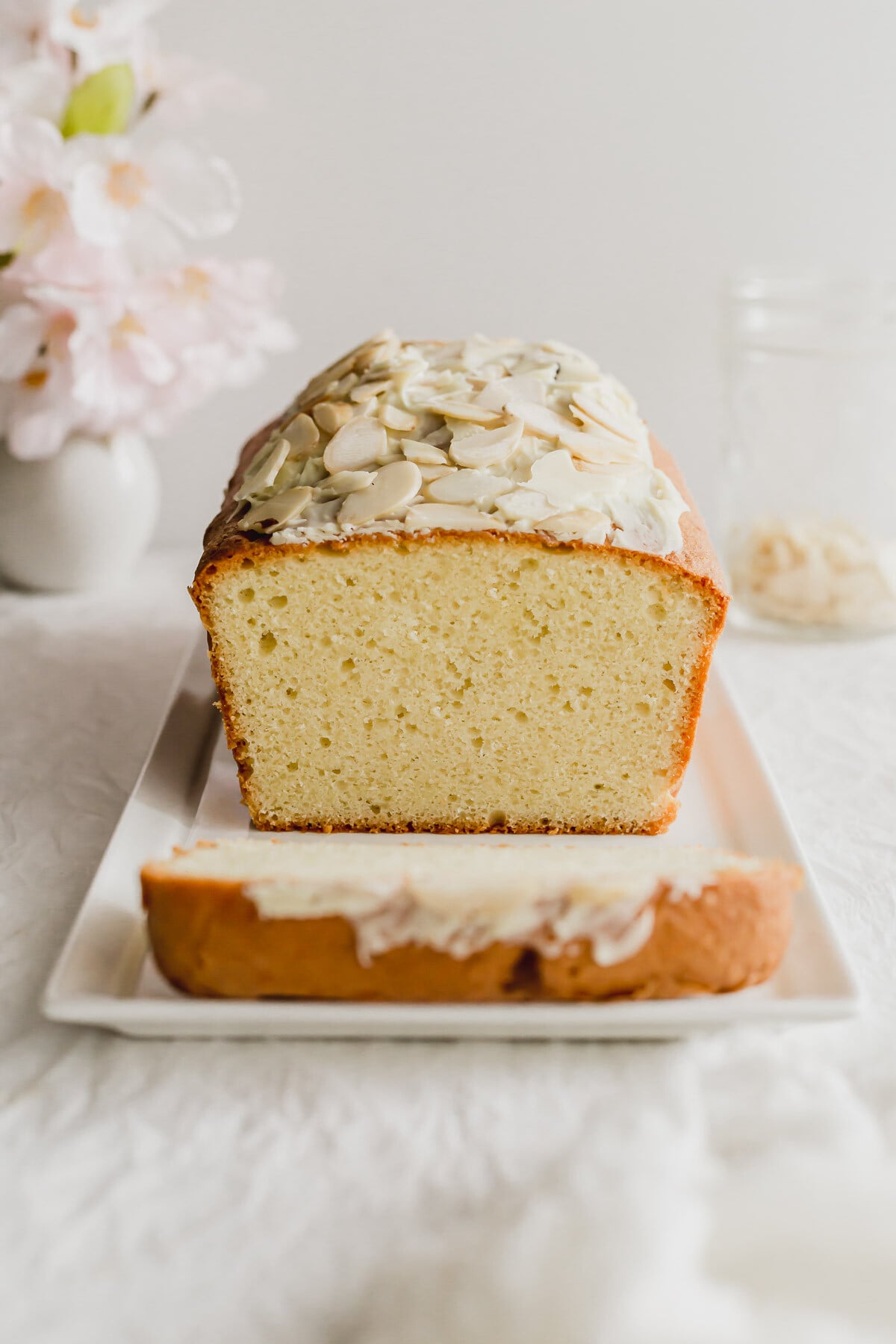 Sliced almond pound cake on a white rectangular plate.