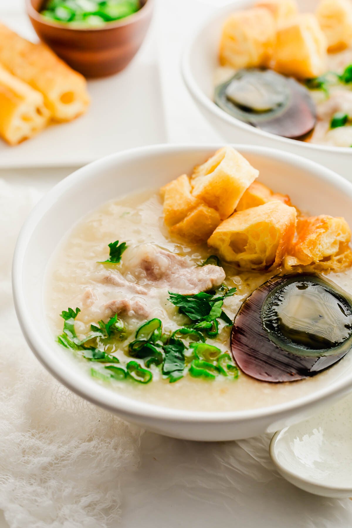 Century egg and pork congee in a white bowl.