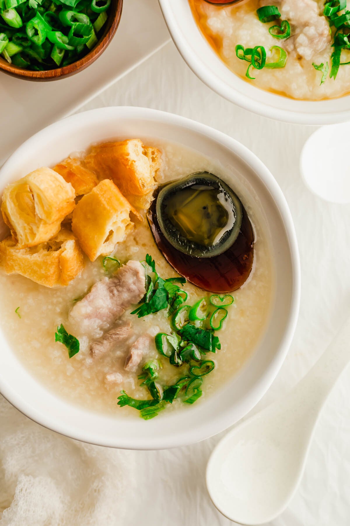 White bowls filled with century egg and pork congee.