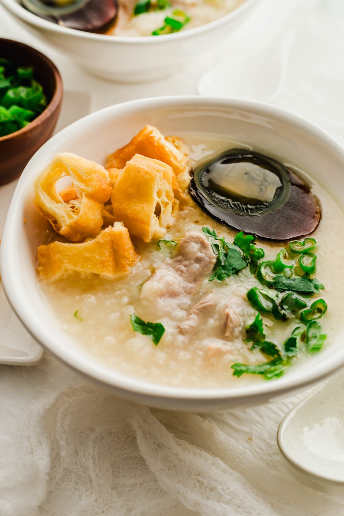 Century egg and pork congee in a white bowl.