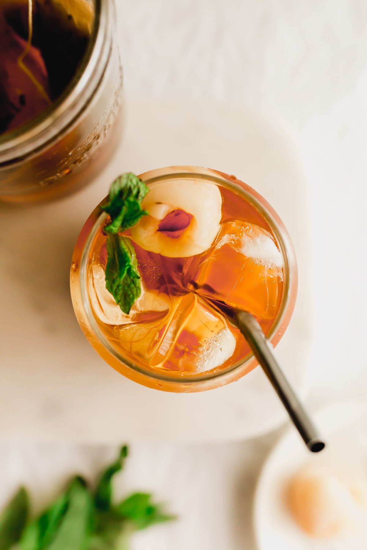 Iced lychee black tea in a glass with straw.
