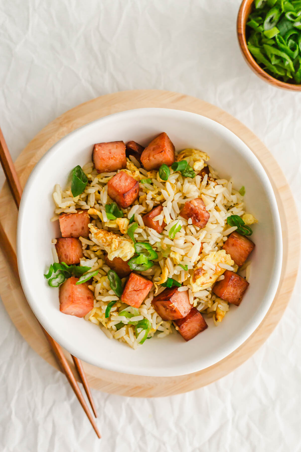 Spam fried rice in a white bowl, with chopsticks on the side.