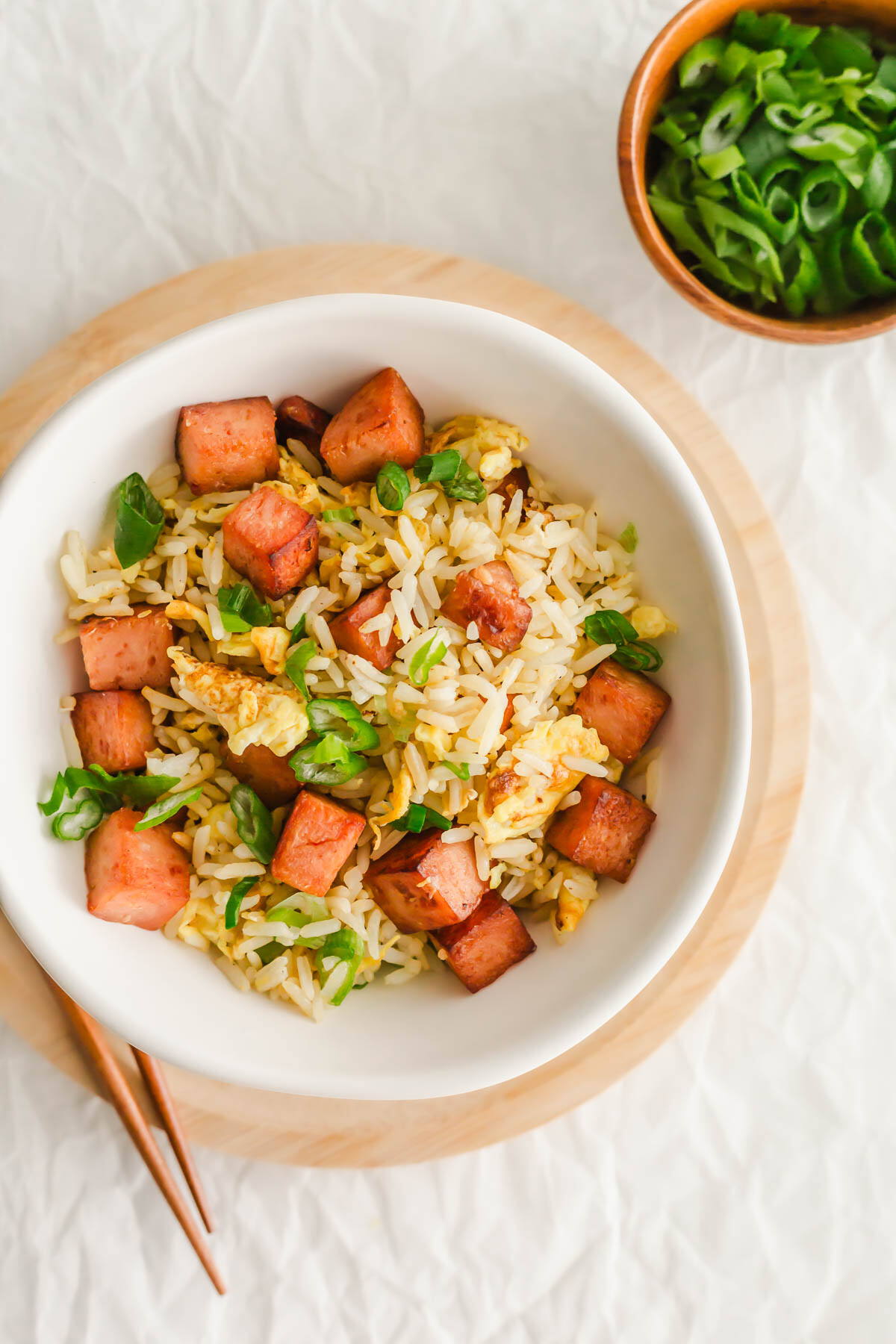 Spam fried rice in a white bowl, with chopsticks on the side.
