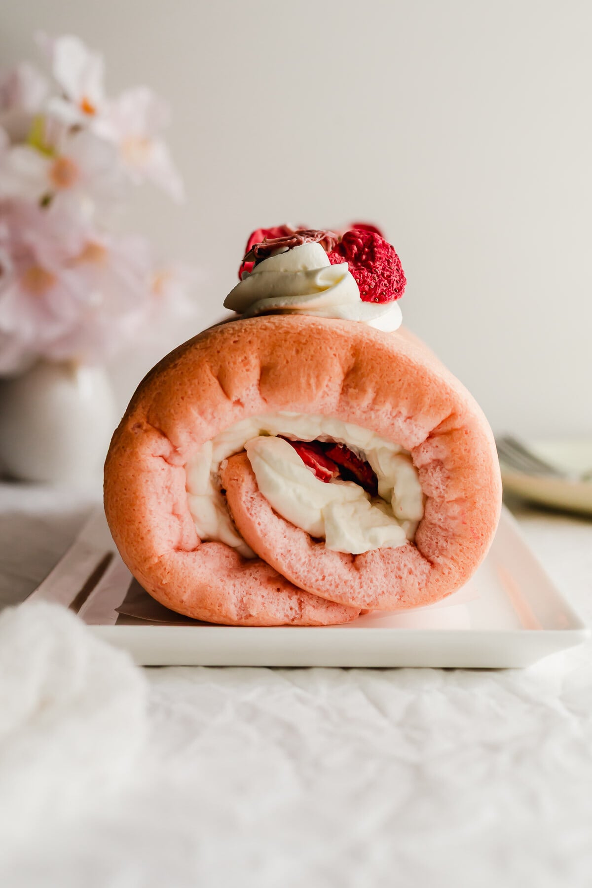 Cherry Blossom roll cake on a white rectangular plate.