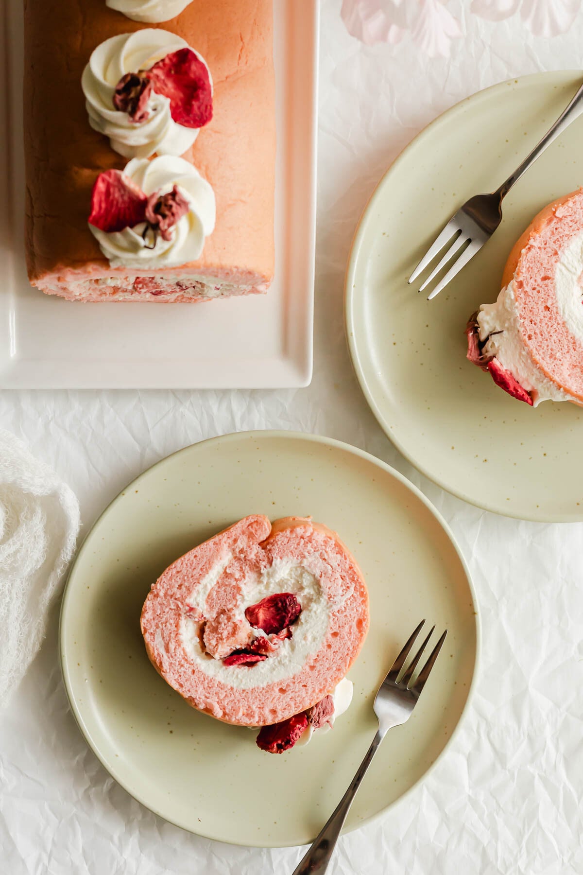 Slices of Cherry Blossom roll cake on green plates with metal forks.