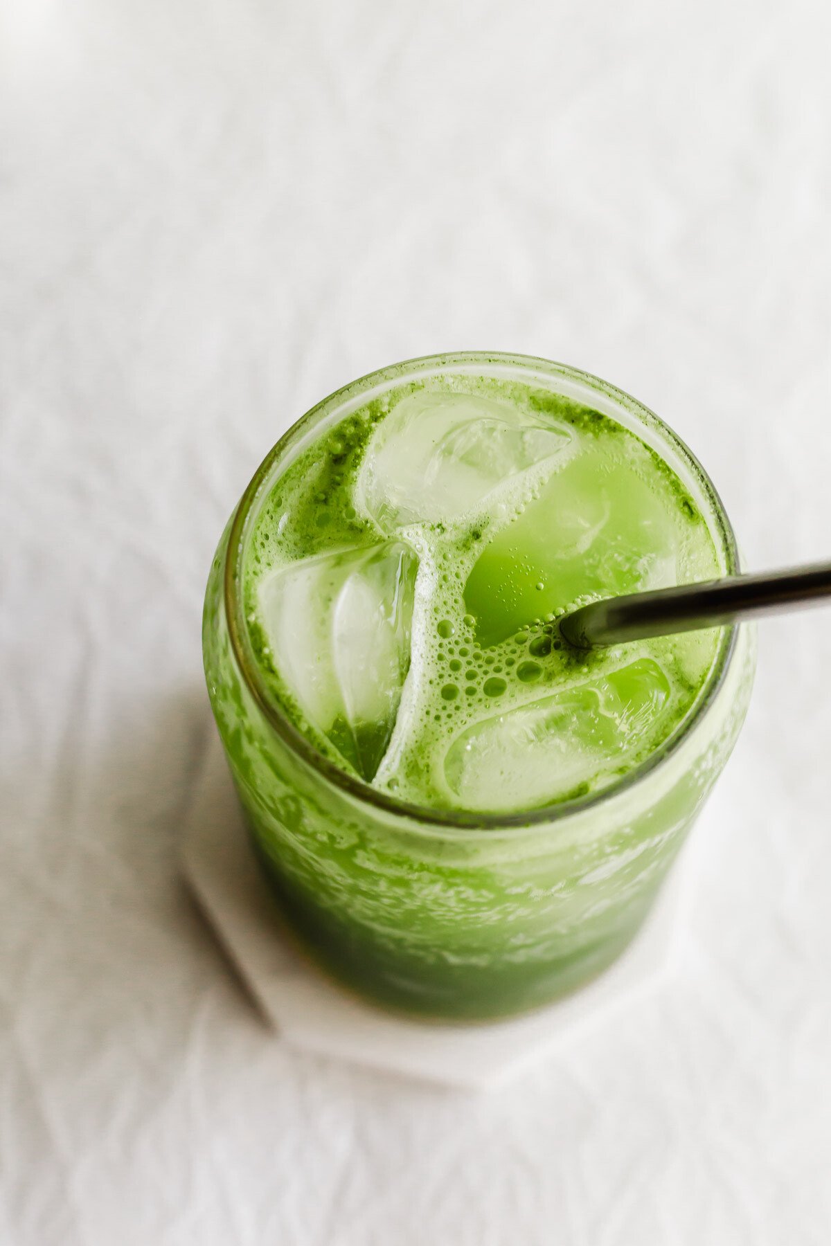 A matcha yuzu drink in a glass with a straw.