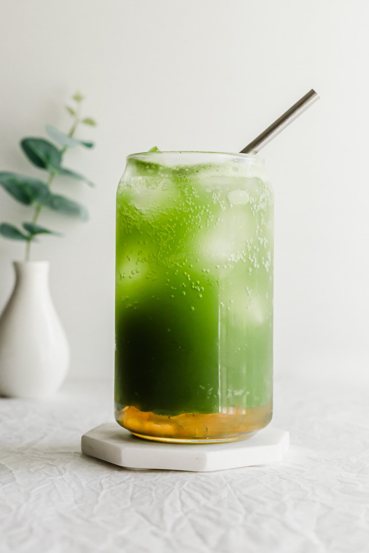 A matcha yuzu drink in a glass with a straw.