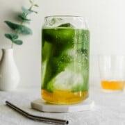 A matcha yuzu drink in a glass with a straw.
