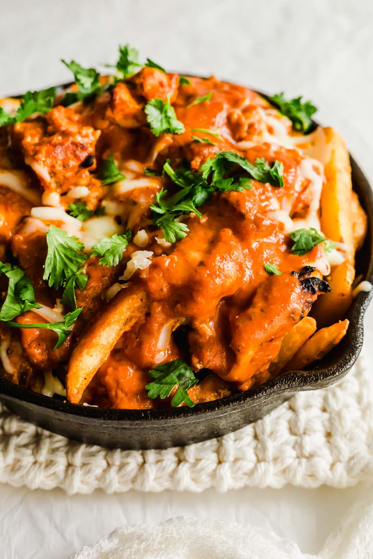 Butter chicken poutine in a skillet.