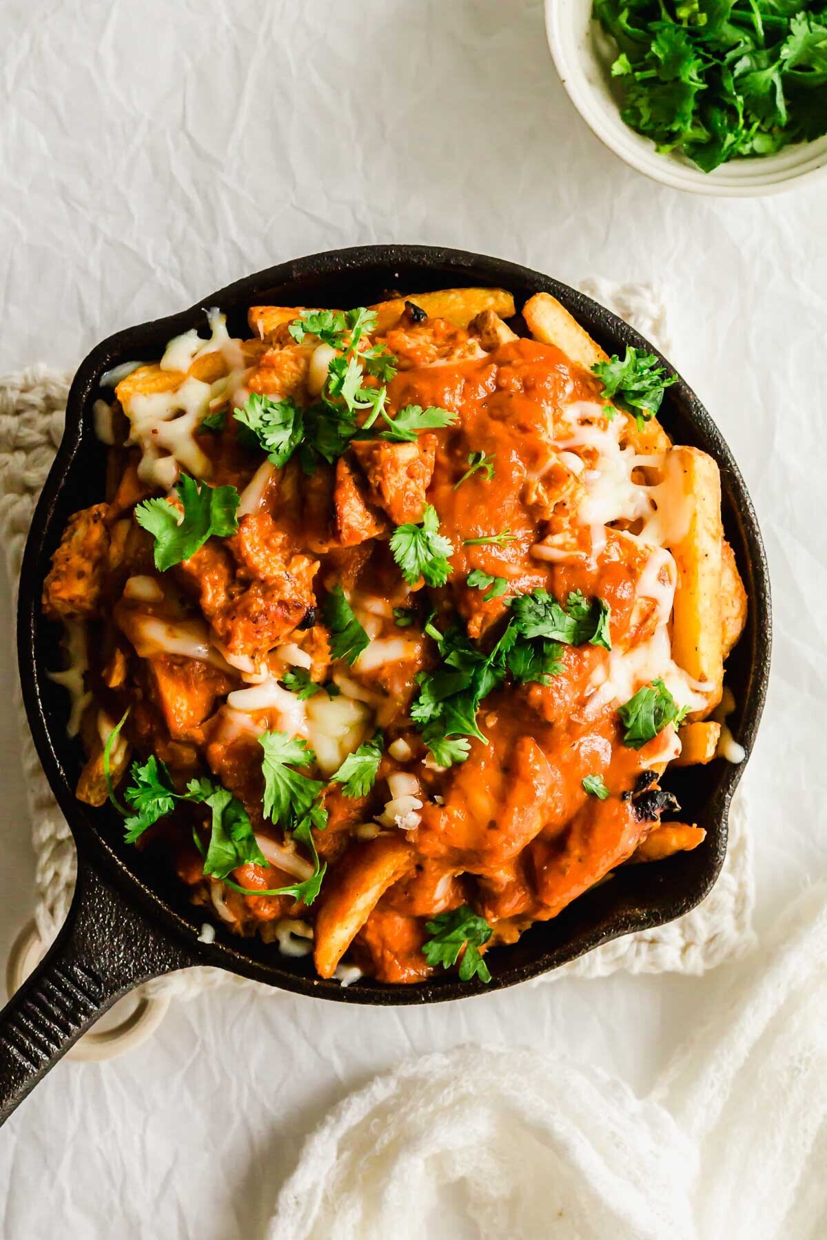 Butter chicken poutine in a skillet.