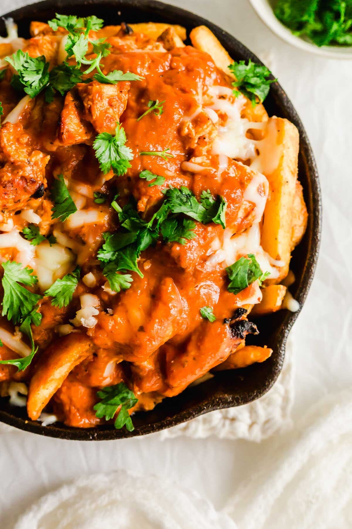 Butter chicken poutine in a skillet.