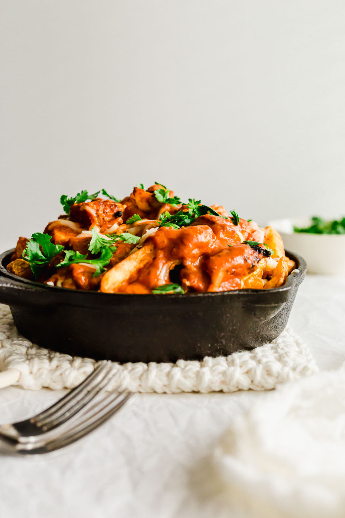 Butter chicken poutine in a skillet.