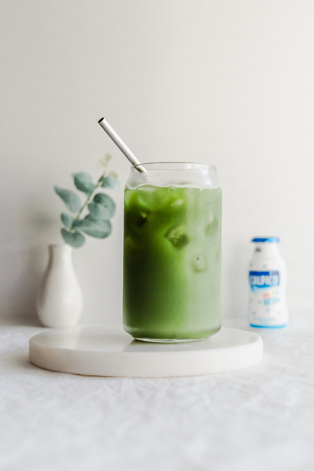 Matcha Calpis in a glass with metal straw.