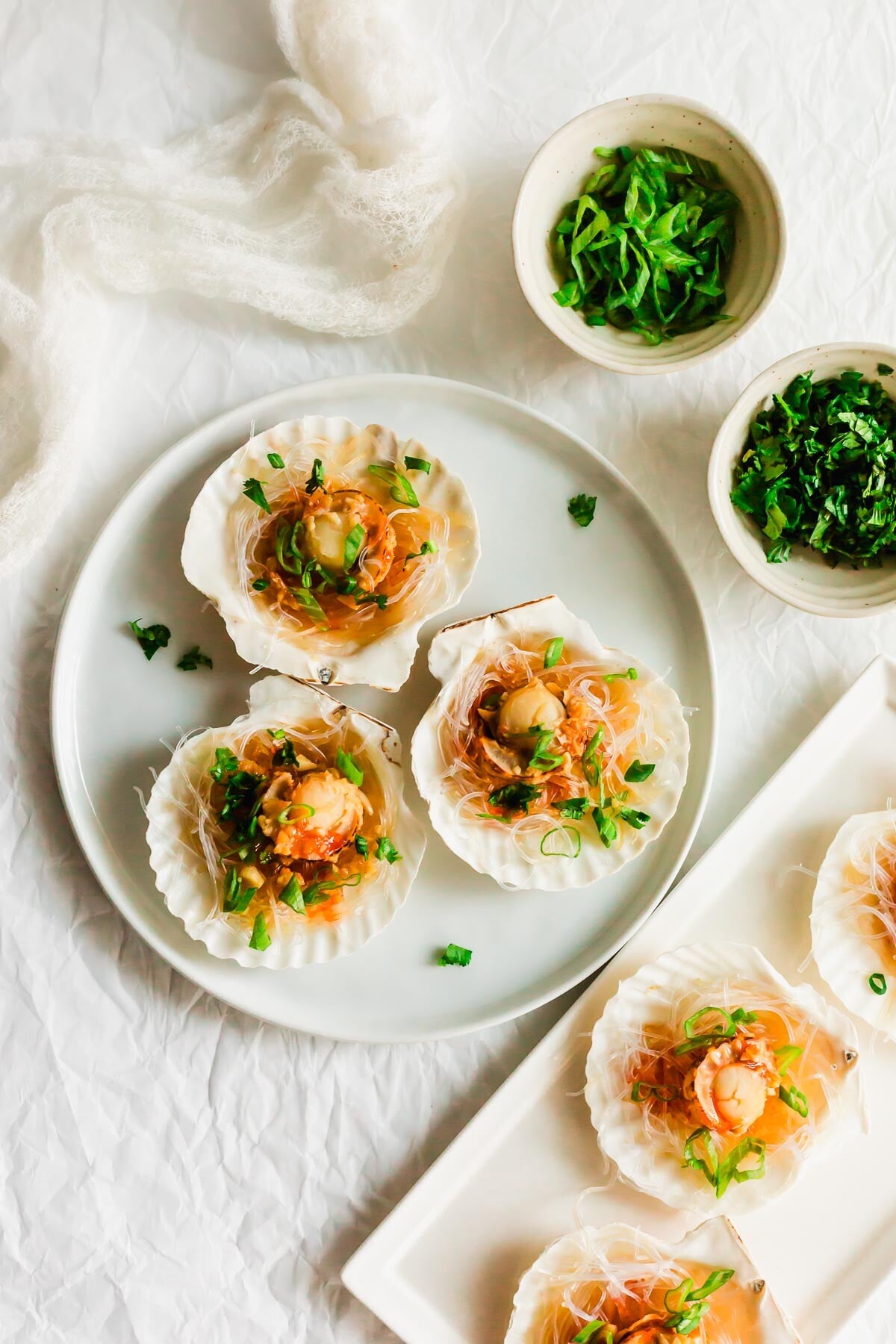 Steamed scallops on a half shell, on white plates.
