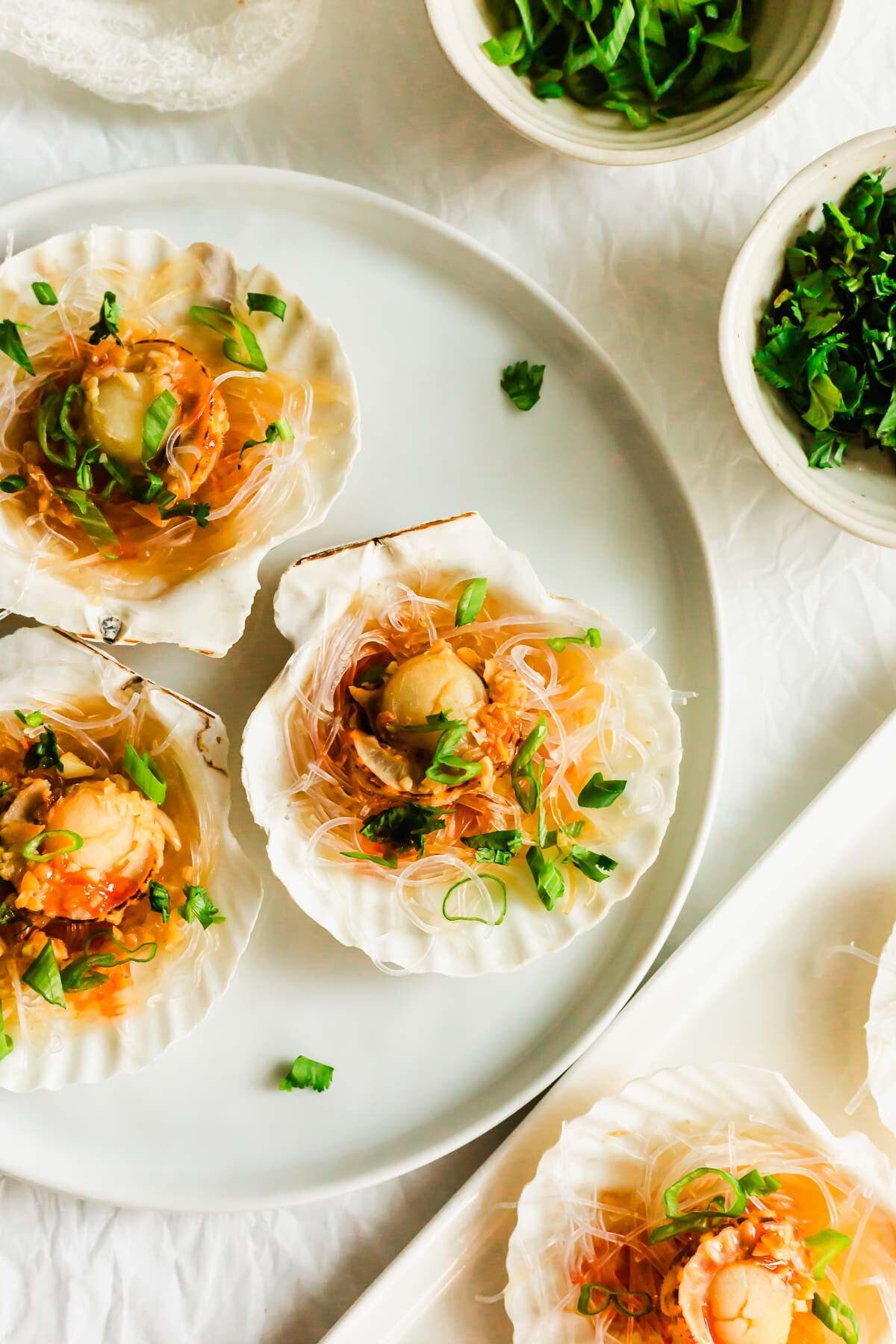Steamed scallops on a half shell, on white plate.