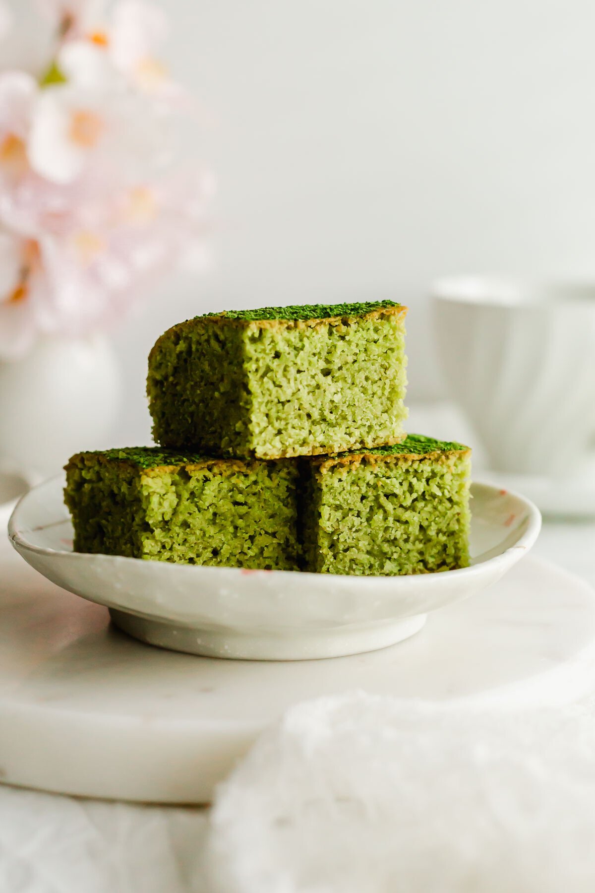 Matcha almond brownies stacked on a white plate.