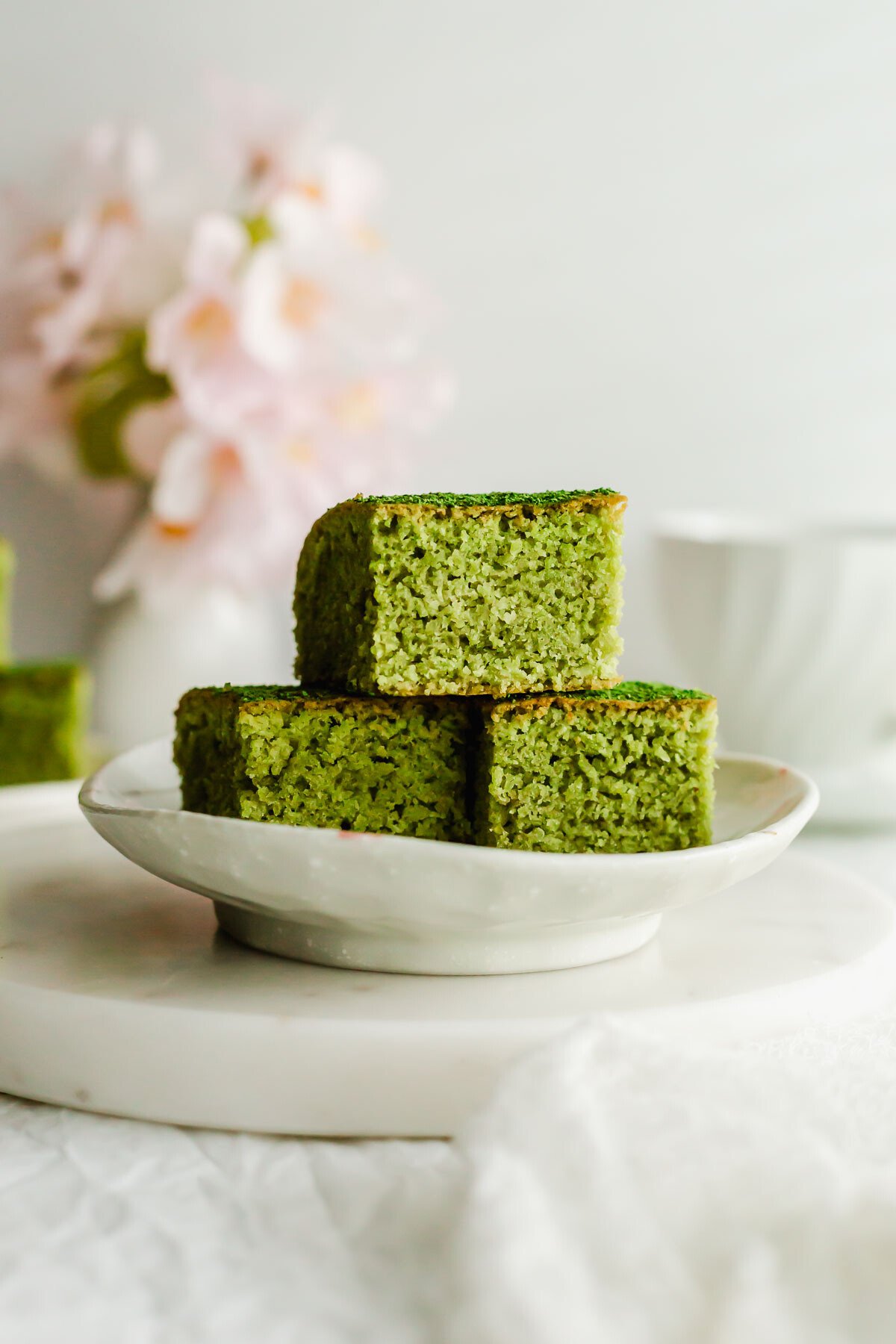 Matcha almond brownies stacked on a white plate.