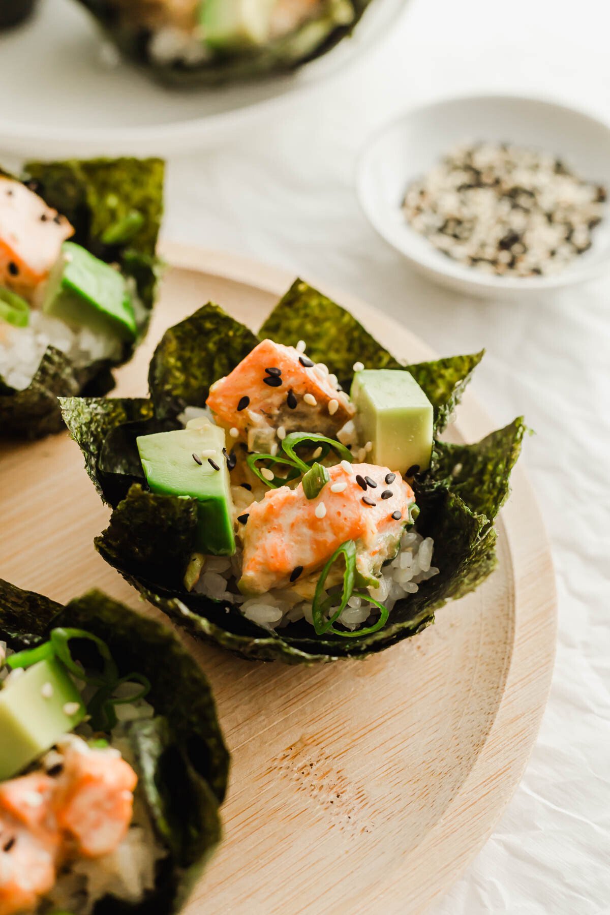 Close up of baked salmon sushi cups on a wooden plate.