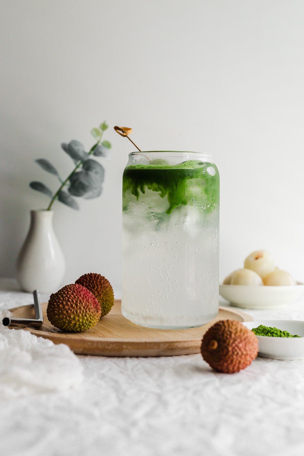 Matcha lychee soda in a glass on wooden plate.