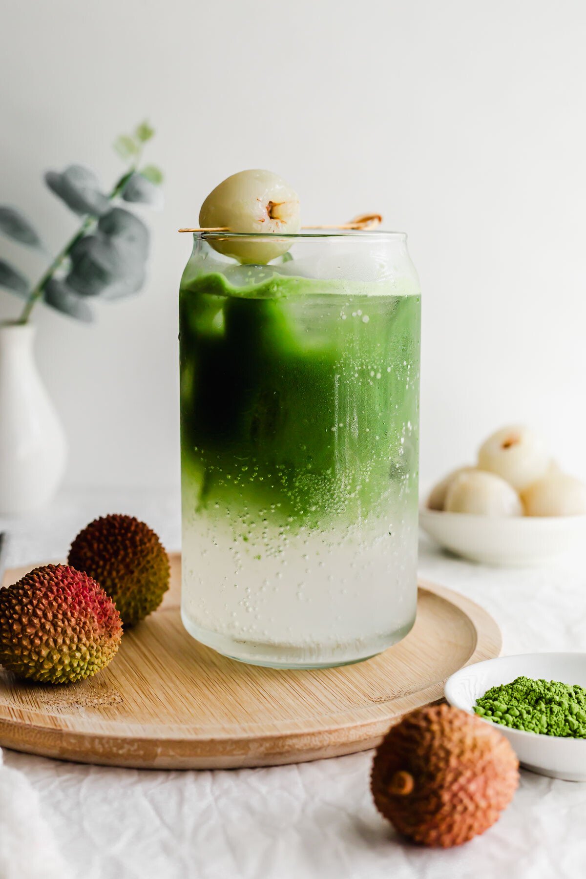 Matcha lychee soda in a glass on wooden plate.