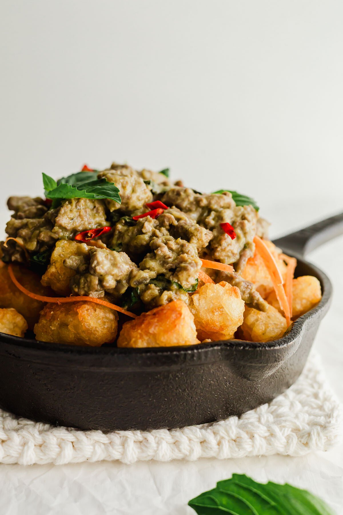 Thai green curry chicken totchos in a black skillet.