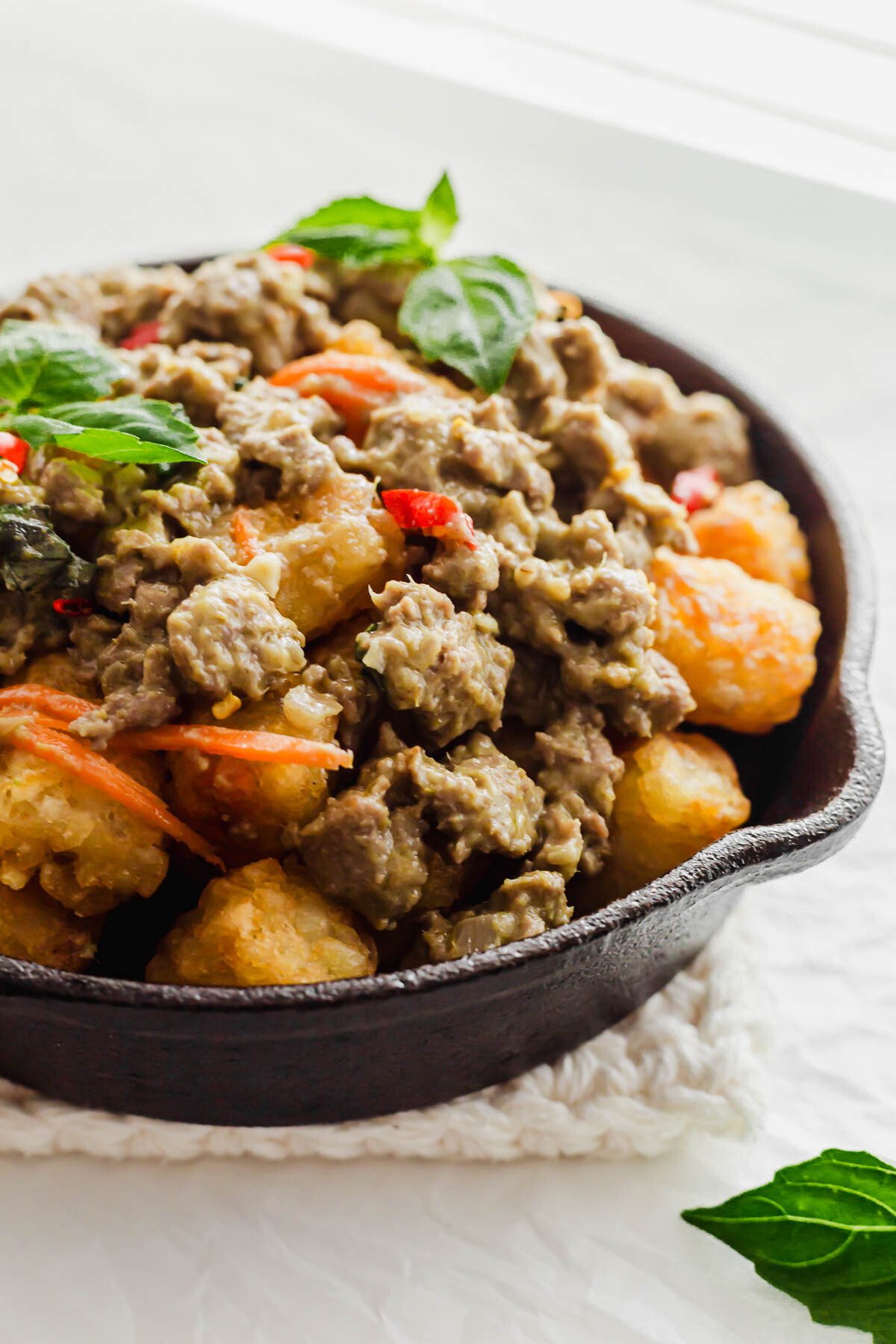 Thai green curry chicken totchos in a black skillet.