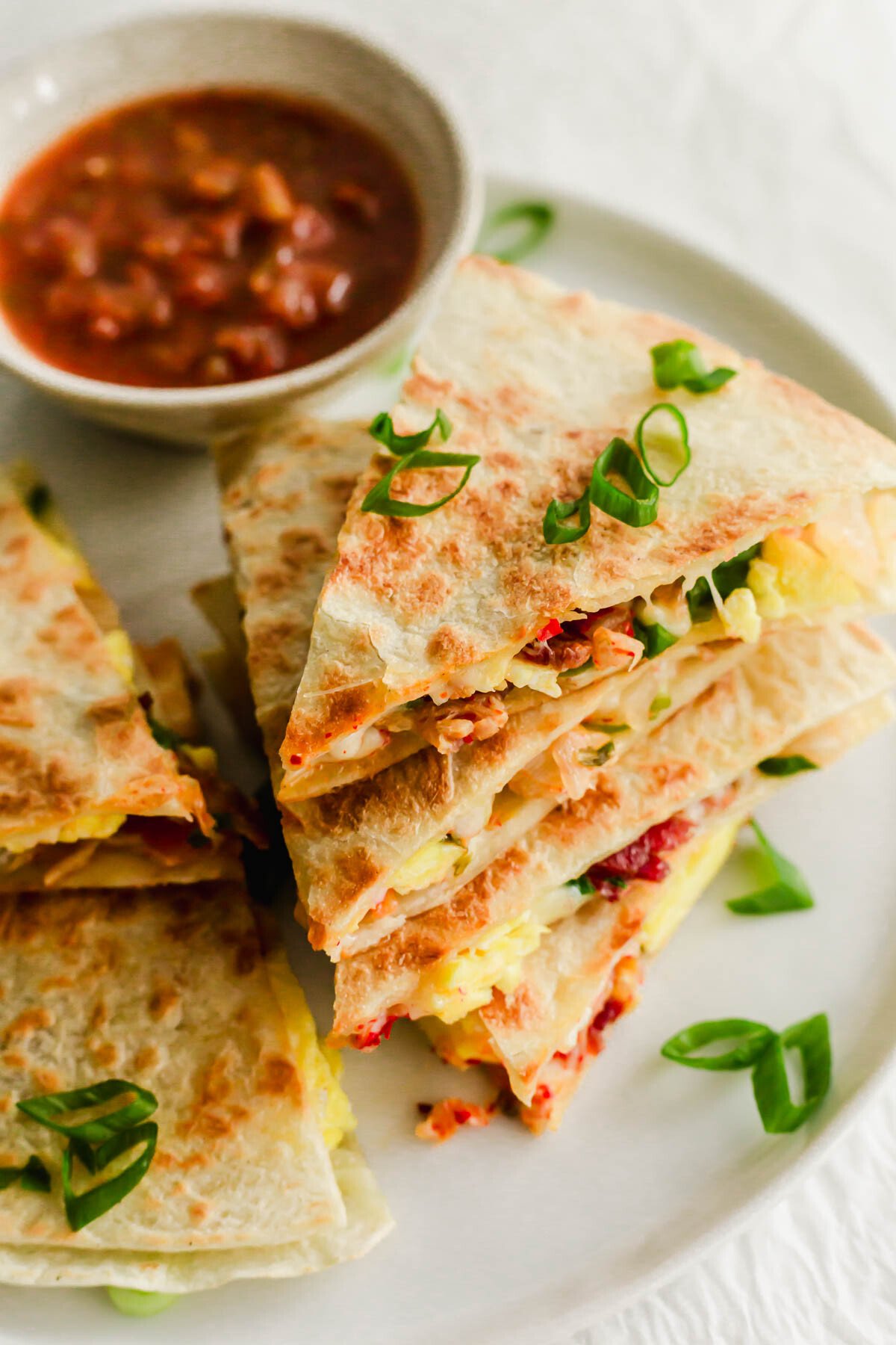 A stack of quesadillas with a side of salsa.