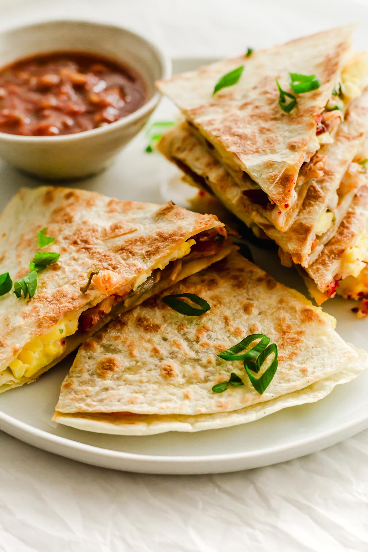 A plate of quesadillas with salsa in a bowl.