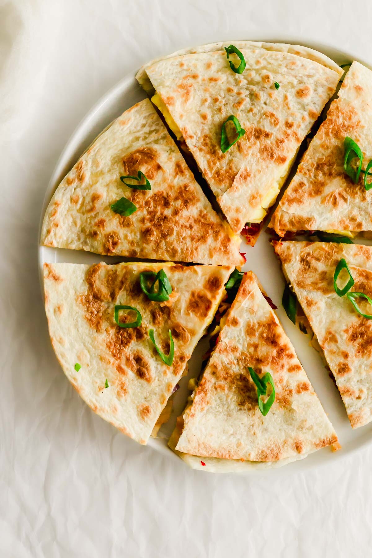 A plate with several quesadillas cut into pieces.