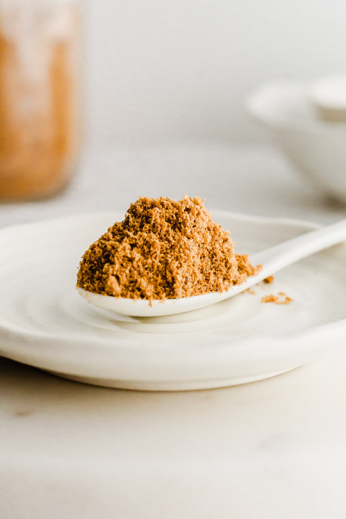 A white spoon filled with Chinese fish flounder powder on a white dish.