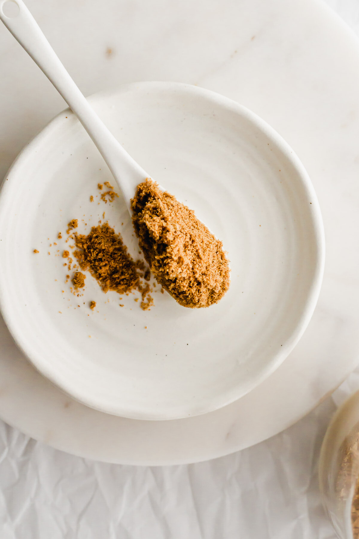 A white spoon filled with Chinese fish flounder powder on a white dish.