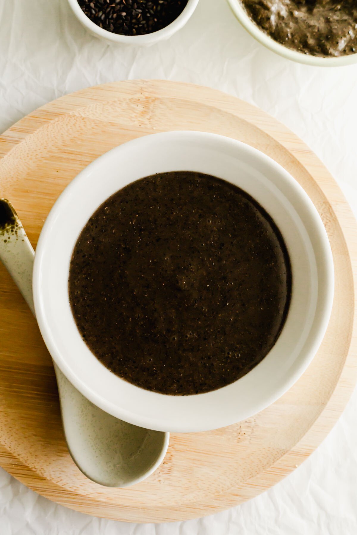 Black sesame soup in a white bowl, with spoon on the side.