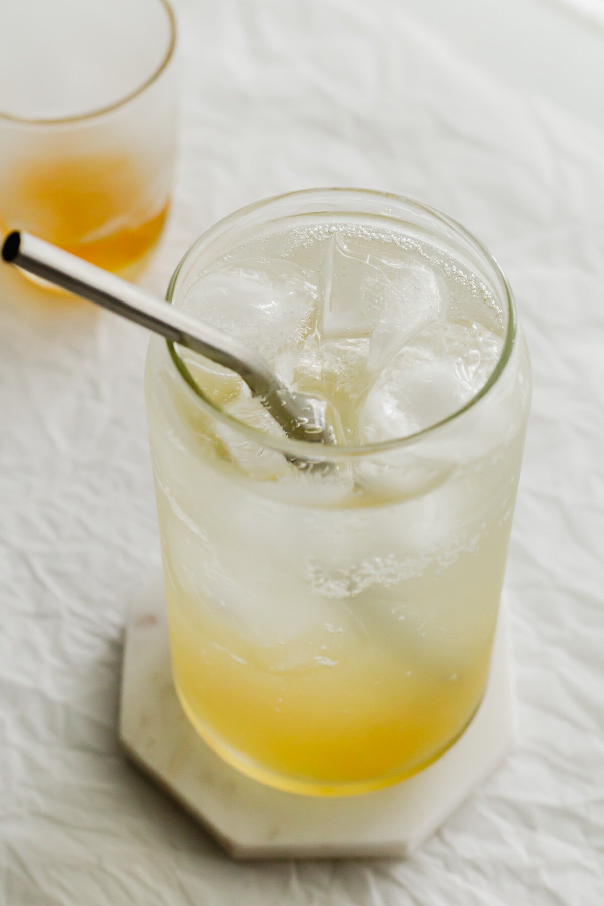 Iced sparkling yuzu in a glass with metal straw.