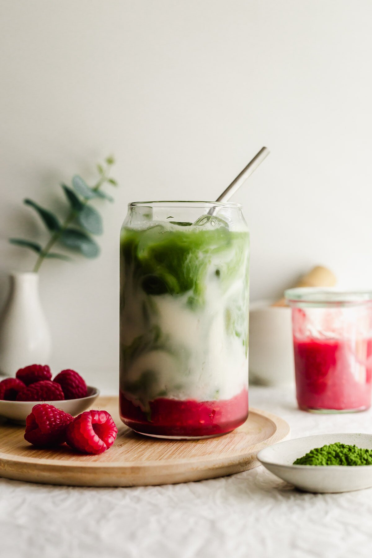Raspberry matcha latte in a glass with straw.