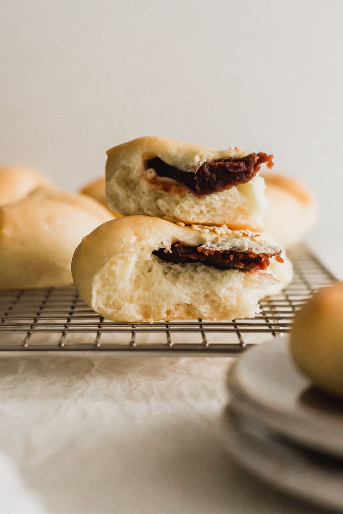 Torn baked red bean buns stacked on top of wire rack.