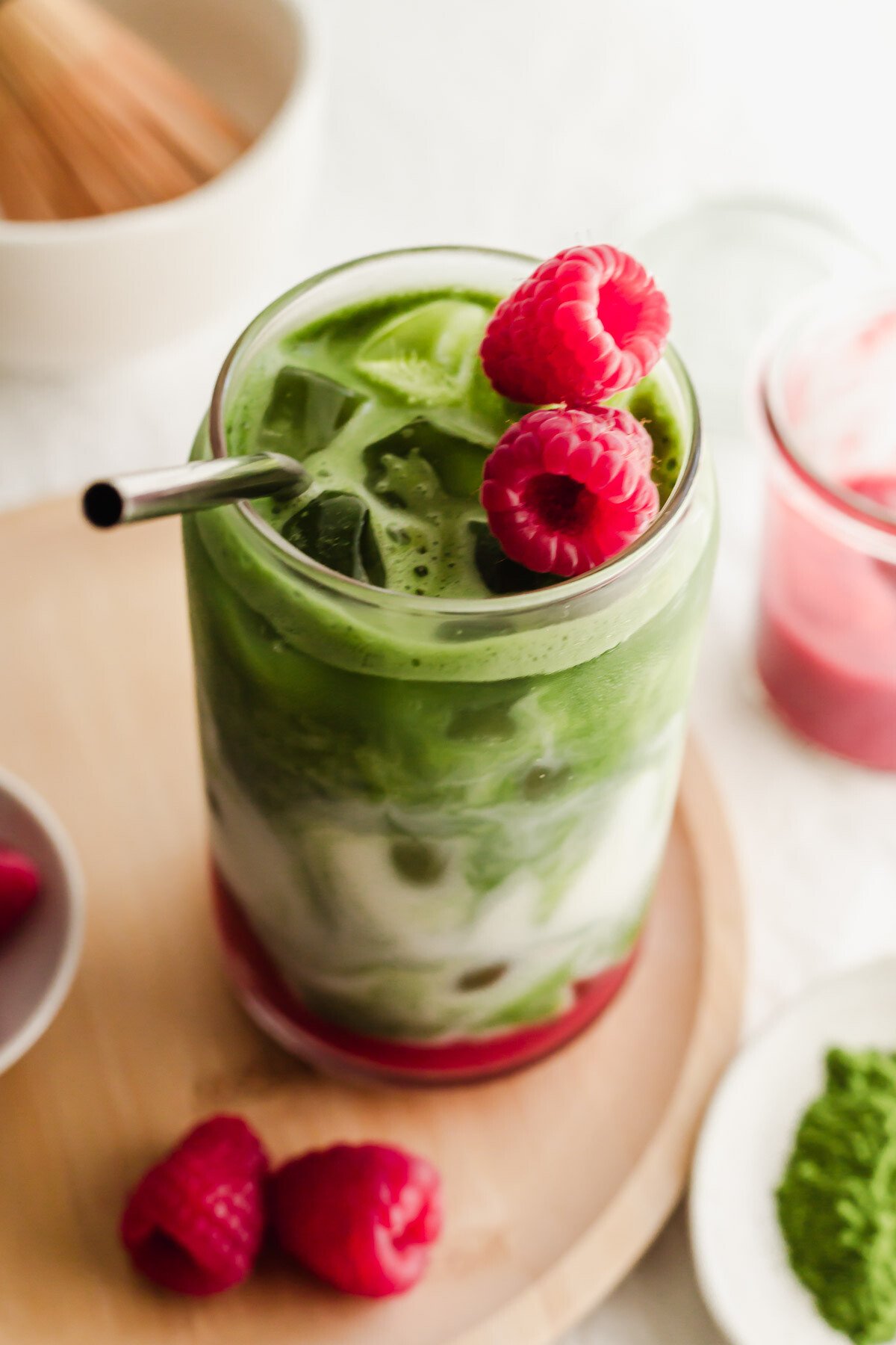 Raspberry matcha latte in a glass with straw.