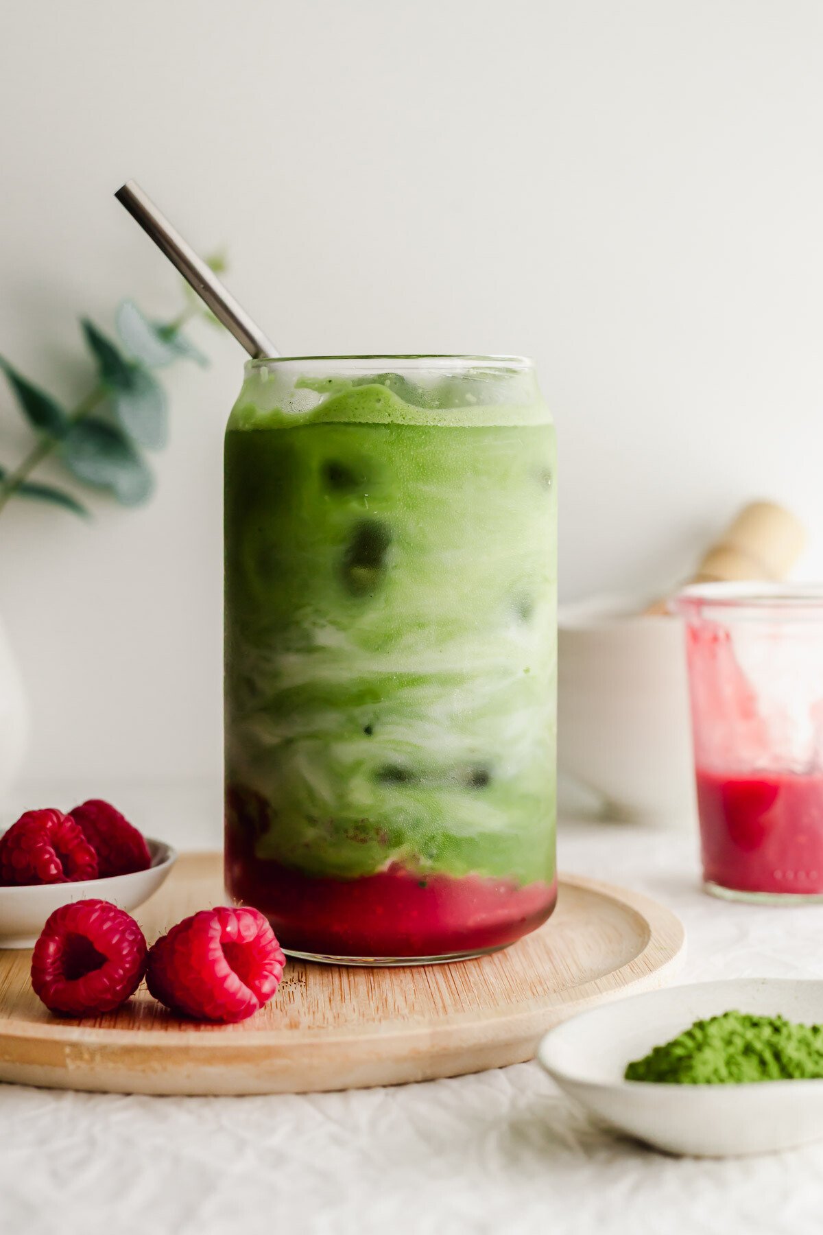 Raspberry matcha latte in a glass with straw.