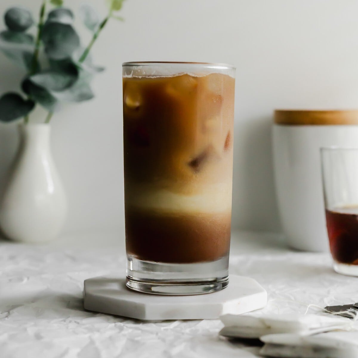 A glass of dirty earl grey latte on white marble coaster.