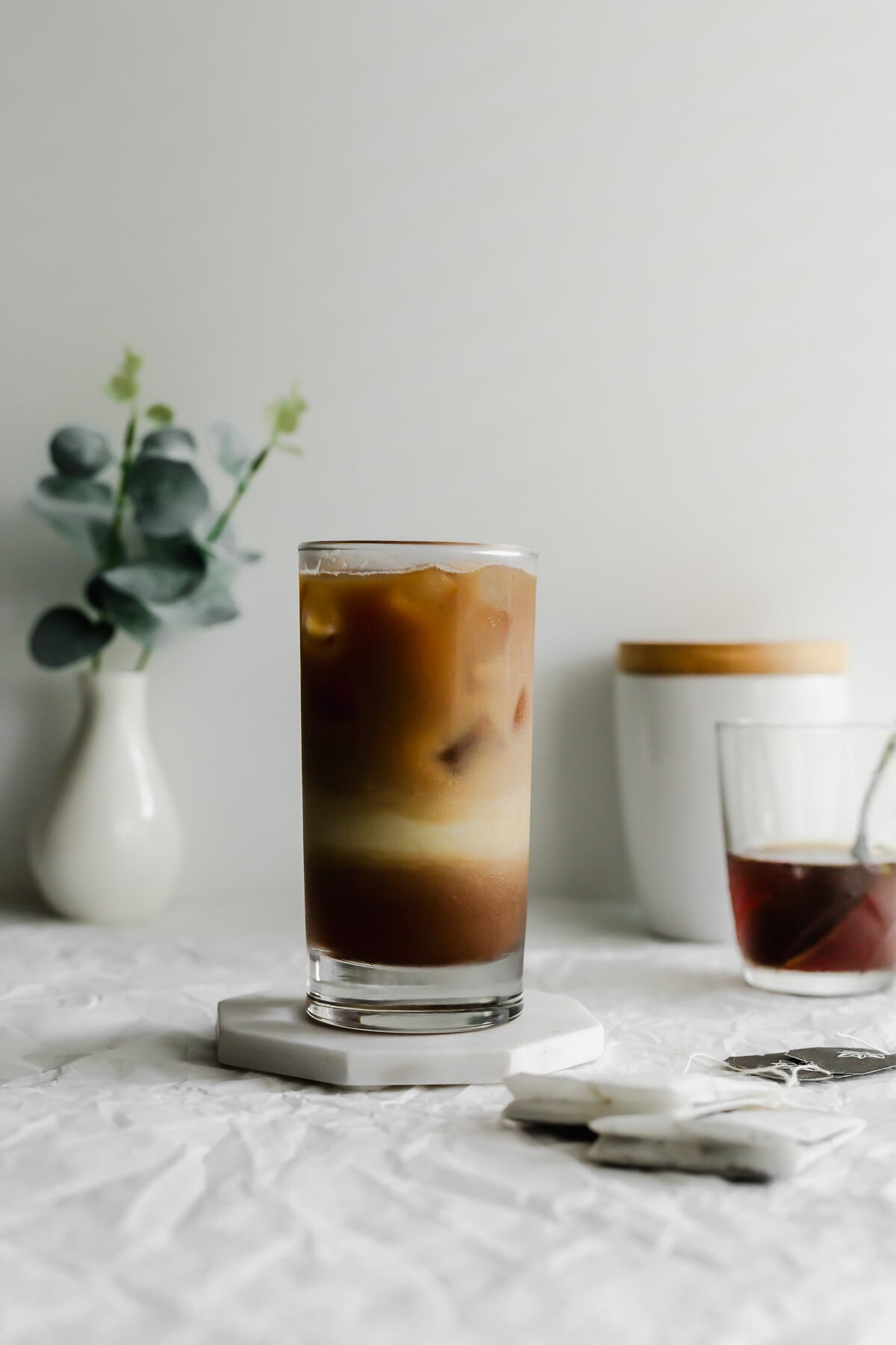 A glass of dirty earl grey latte on white marble coaster.