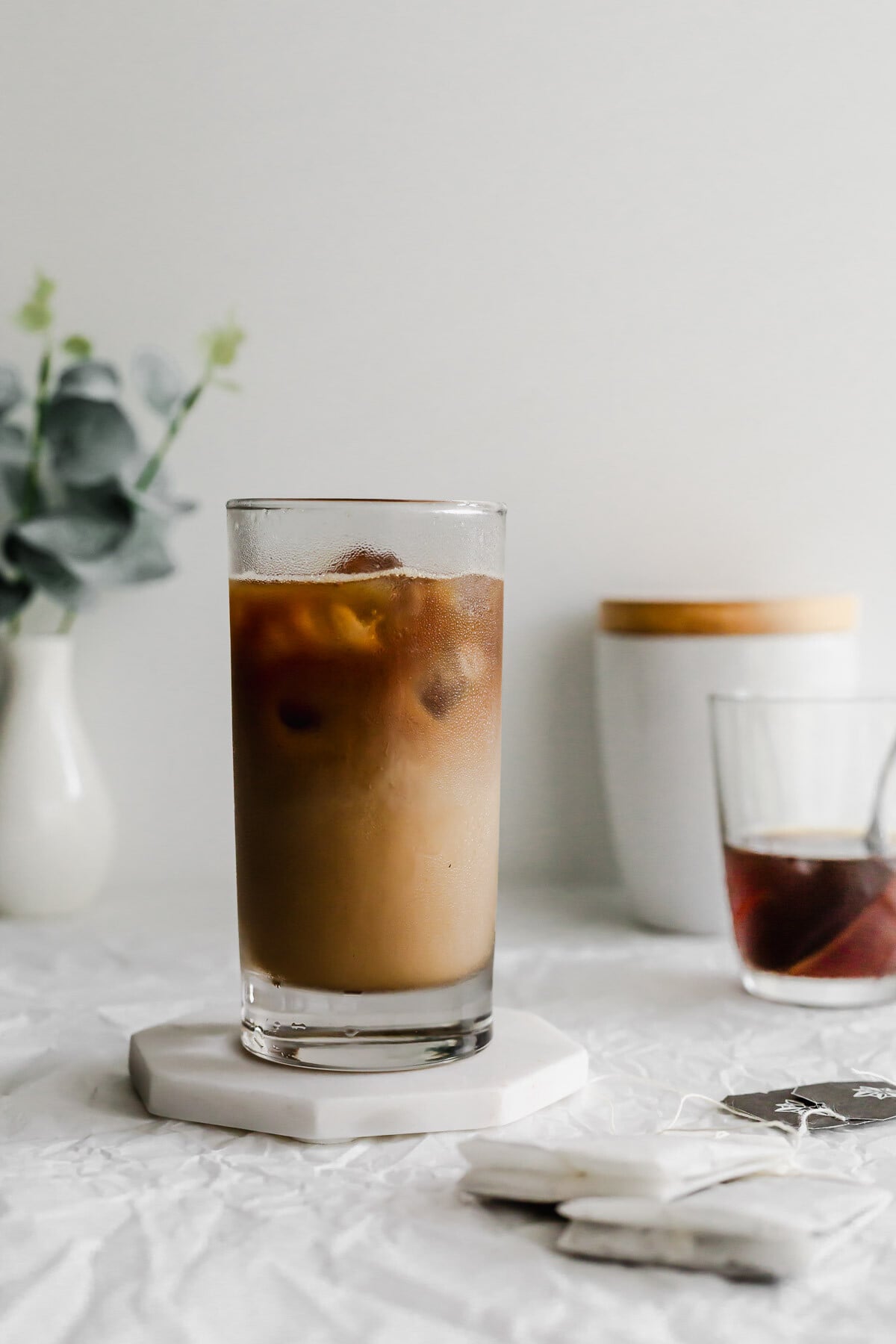 A glass of dirty earl grey latte on white marble coaster.