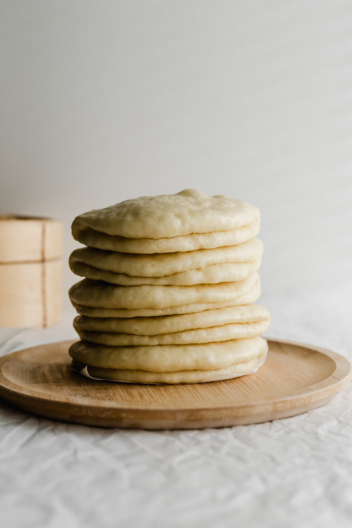 Chinese bao buns stacked on a wooden plate.