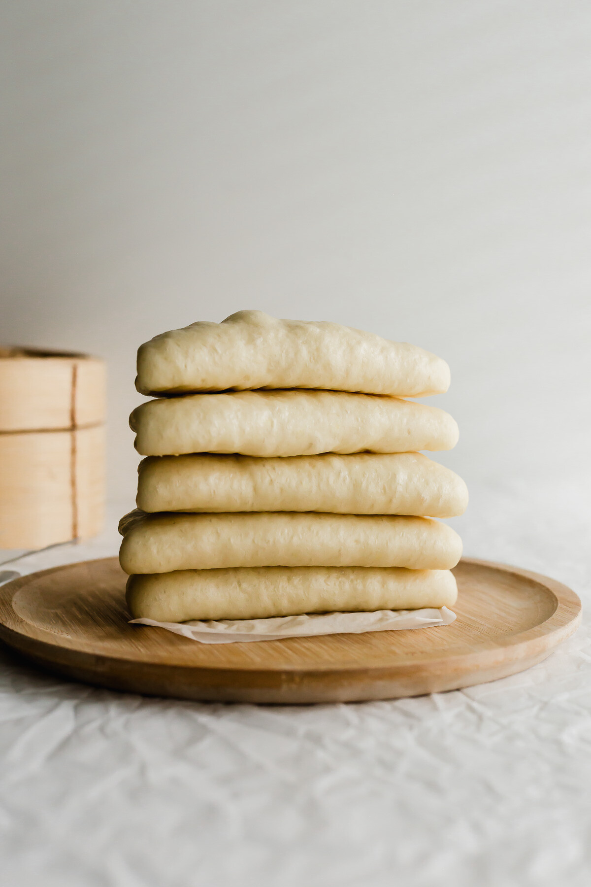 A wooden plate piled with steamed Chinese bao buns.