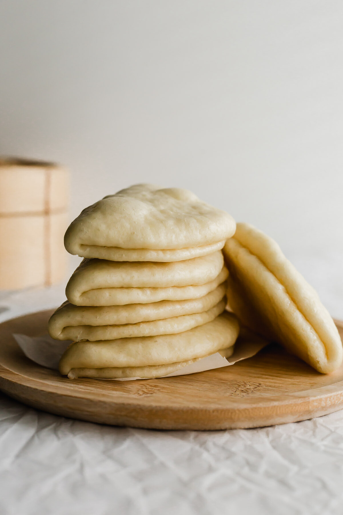 Steamed Chinese lotus leaf bao buns stacked on a wooden plate.
